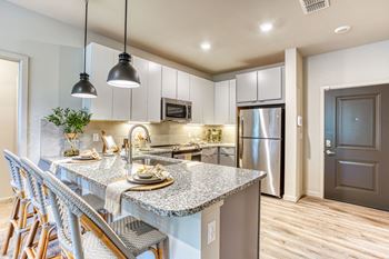 a kitchen with a marble counter top and a stainless steel refrigerator at The Beck at Hidden River, Tampa